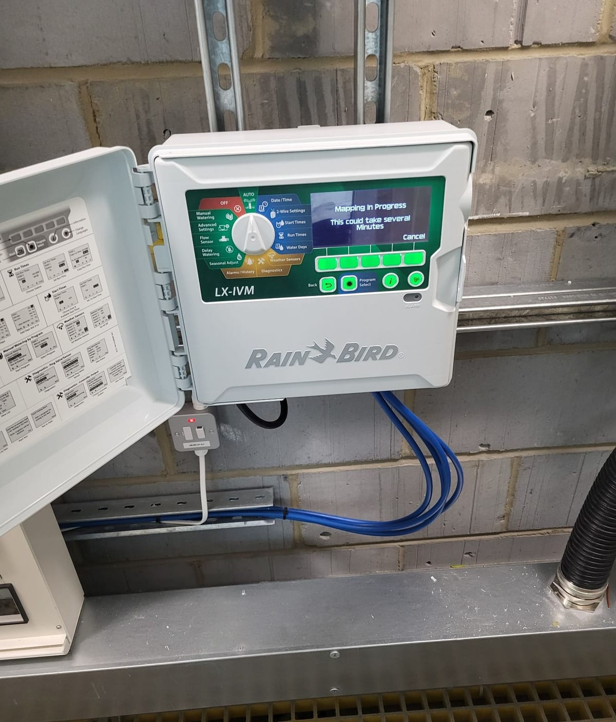 Wall-mounted irrigation controller with its cabinet door open at Uno Golden Lane.